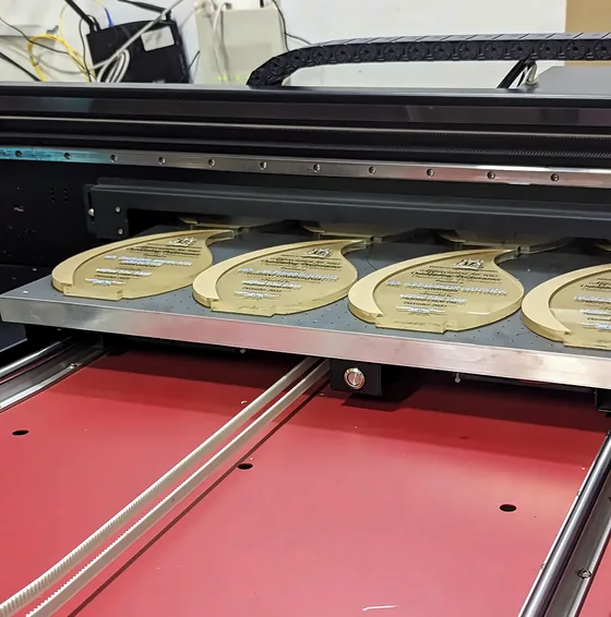 Gold plaques laid out on the bed of a flatbed printer.