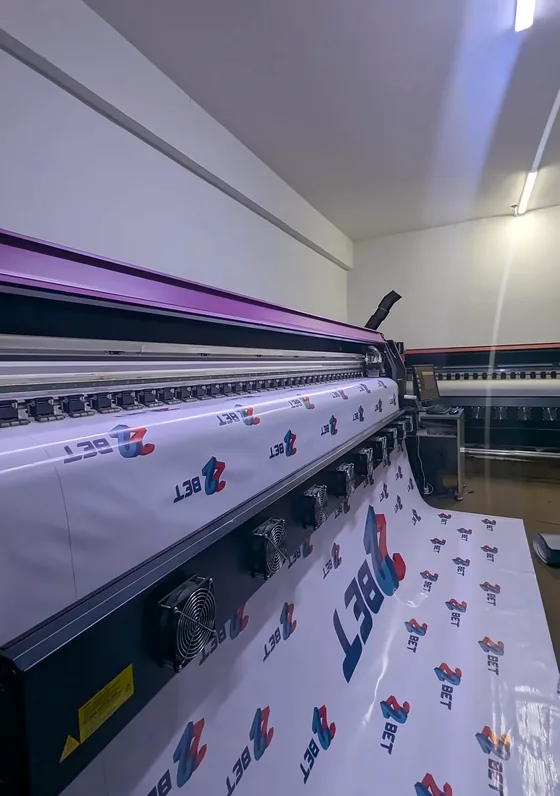 A wide-format printer printing a repeating logo banner.