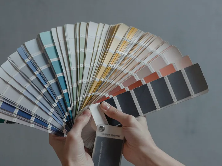 Hands fanning open a colour swatch book.