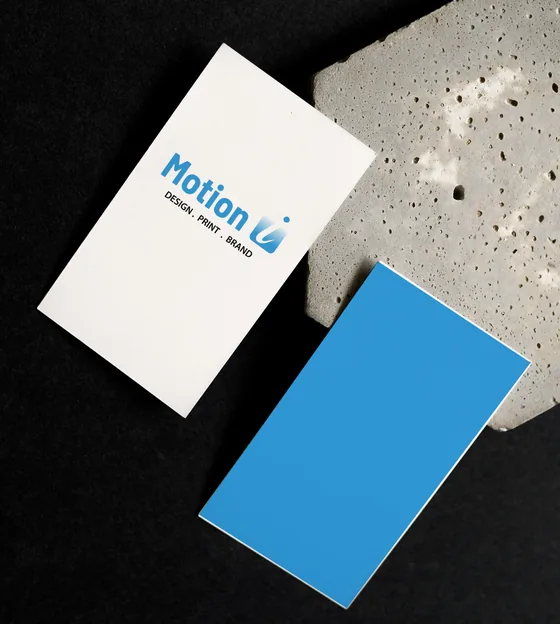 A white business card with the Motion Imprints logo beside a Motion-blue card, on black.