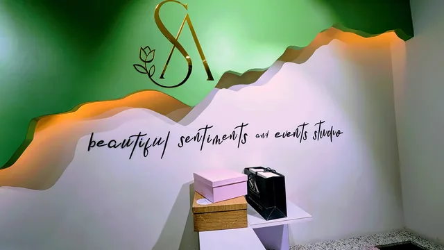 Feature wall with a gold monogram, a layered green panel and script lettering.