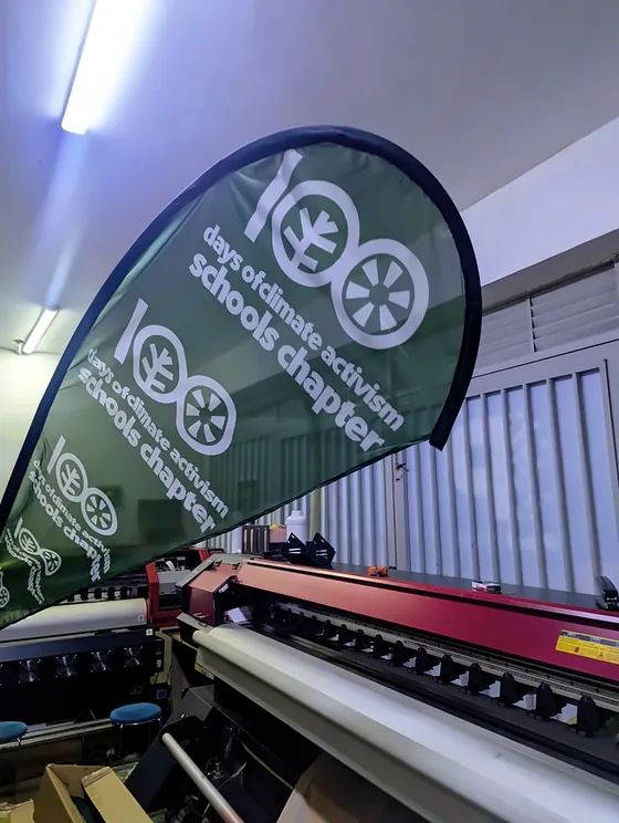 A green teardrop flag printed for a climate activism schools chapter.