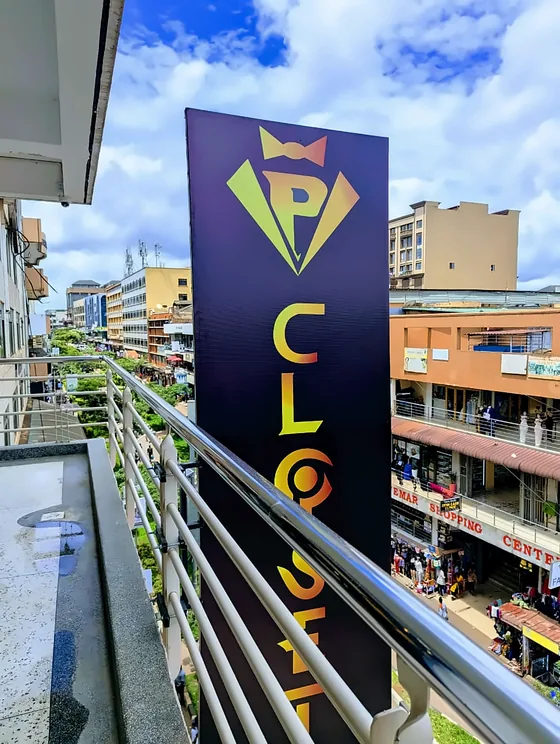 Tall purple and gold blade sign projecting from a balcony over a busy street.