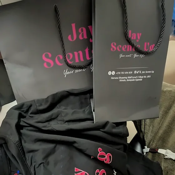 Black Jay Scents carrier bags and garment printed in pink script.