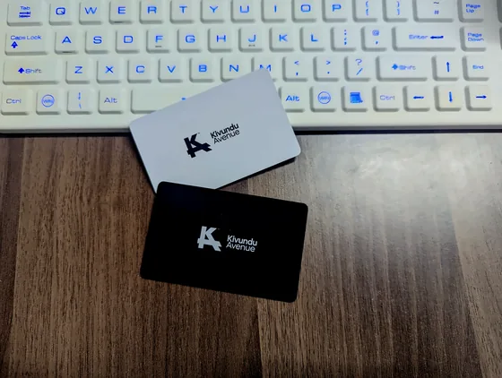 A white and a black Kivundu Avenue business card beside a keyboard.