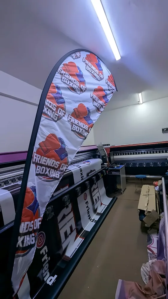 A printed feather flag standing inside a print workshop.
