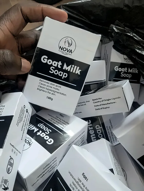A pile of printed Nova goat milk soap boxes, one held up to the camera.